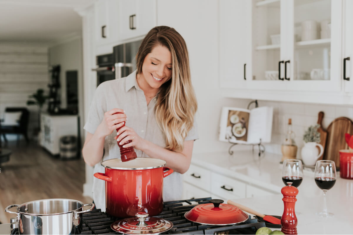 Lady adding seasoning to a tall pot
