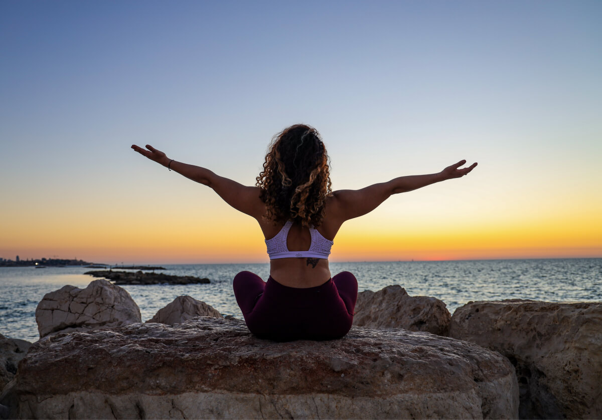 Lady sitting on rock at sunset